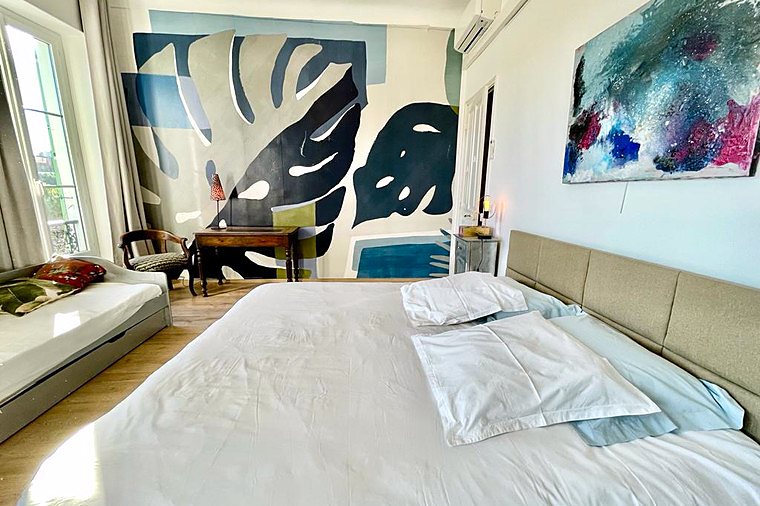 The Leaves room: white bed, leaf mural, sofa and two windows onto the street