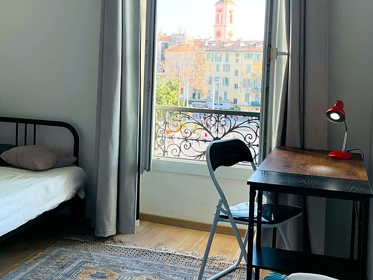 The White room: the bed, the desk and the tall windows over the rooftops and the bell tower