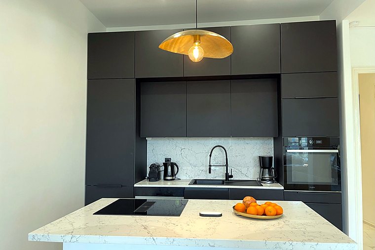 The fully equipped kitchen, black cabinets and marble worktop